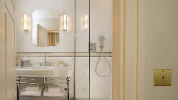A modern bathroom with a glass shower enclosure, a vanity with a sink and mirror, and a towel rack.