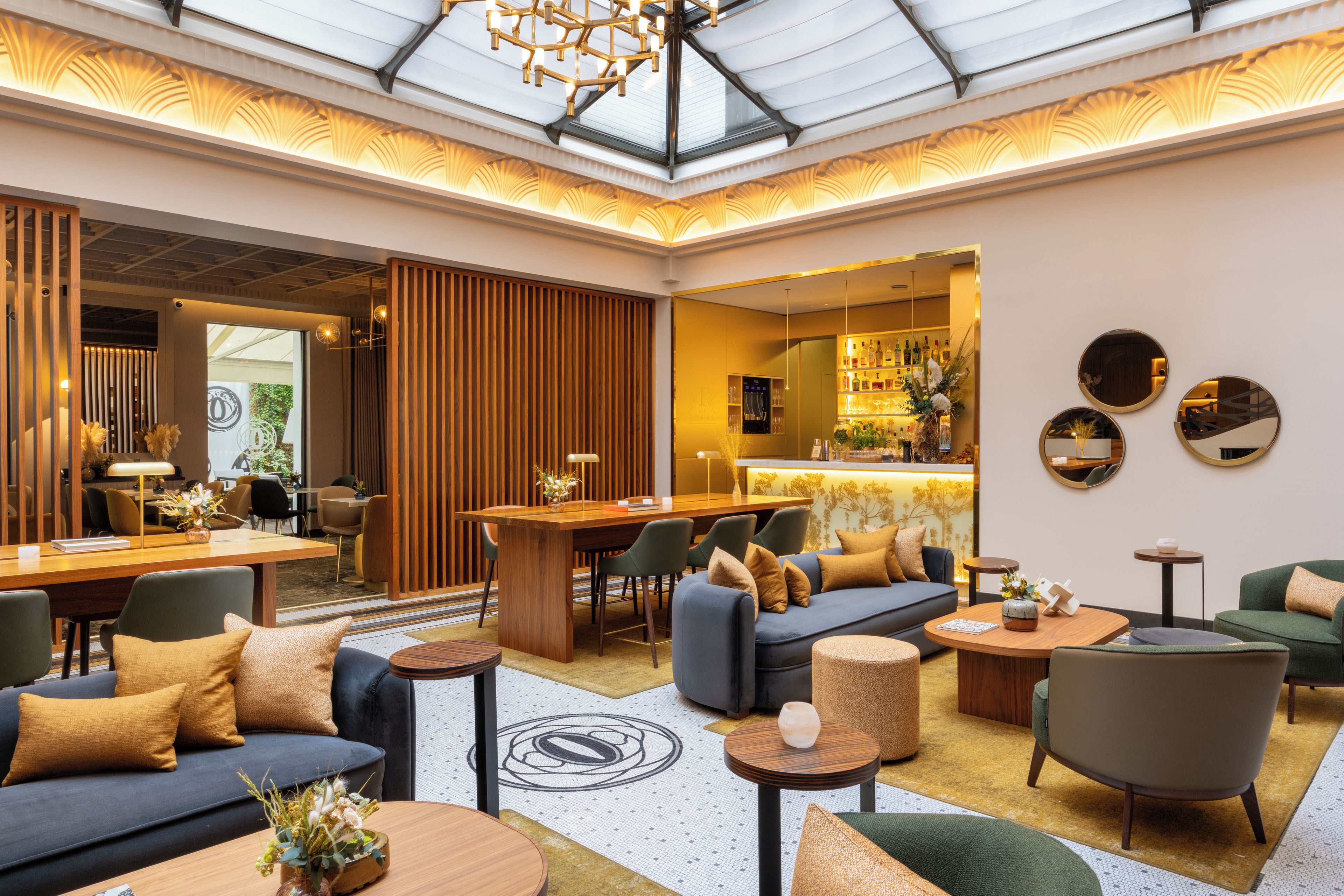 Un lobby amplio con techo alto, zona de estar con sofás y sillones, barra y mostrador de recepción.