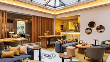 Un lobby amplio con techo alto, zona de estar con sofás y sillones, barra y mostrador de recepción.