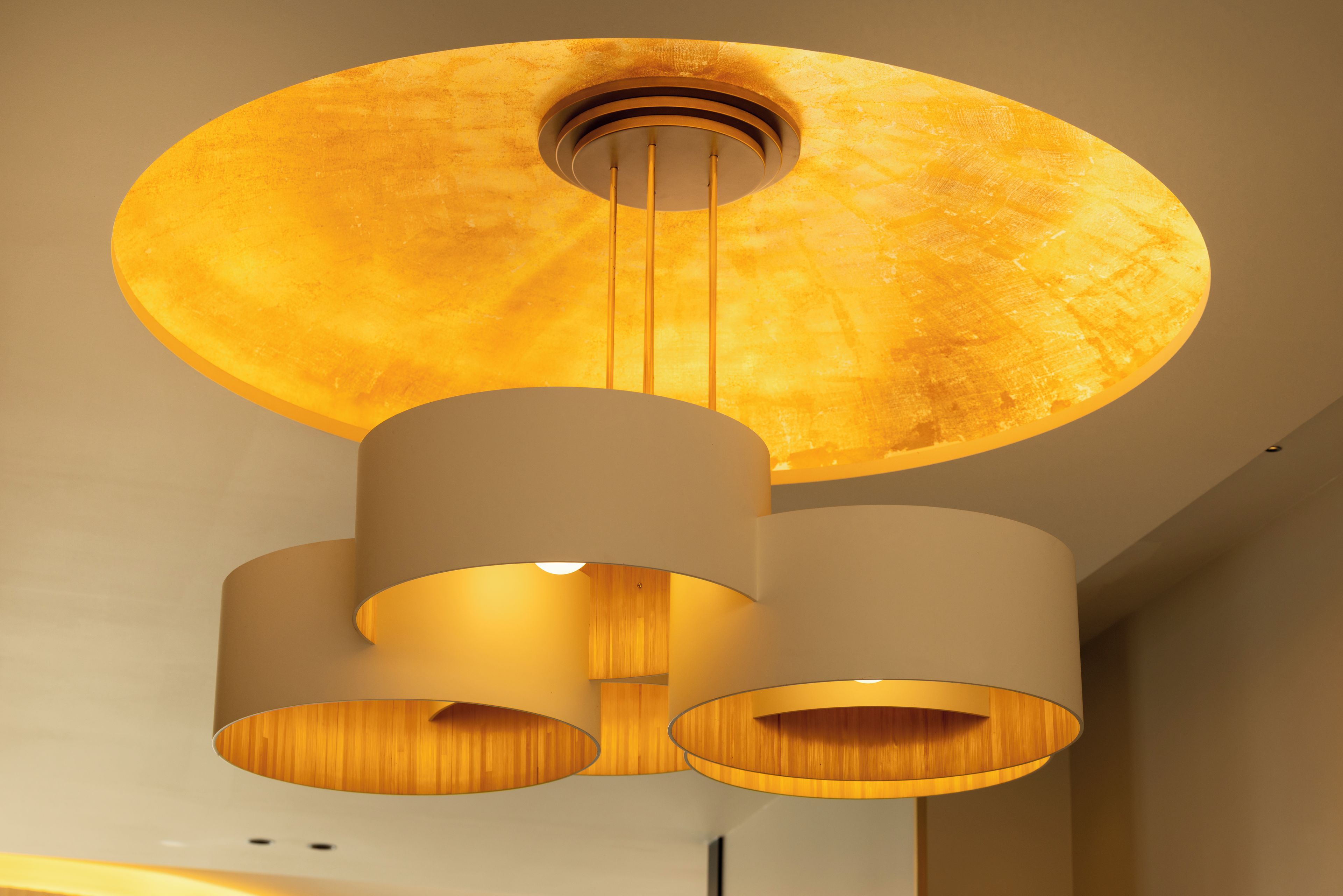 A modern chandelier with a circular shade and three cylindrical lamps.