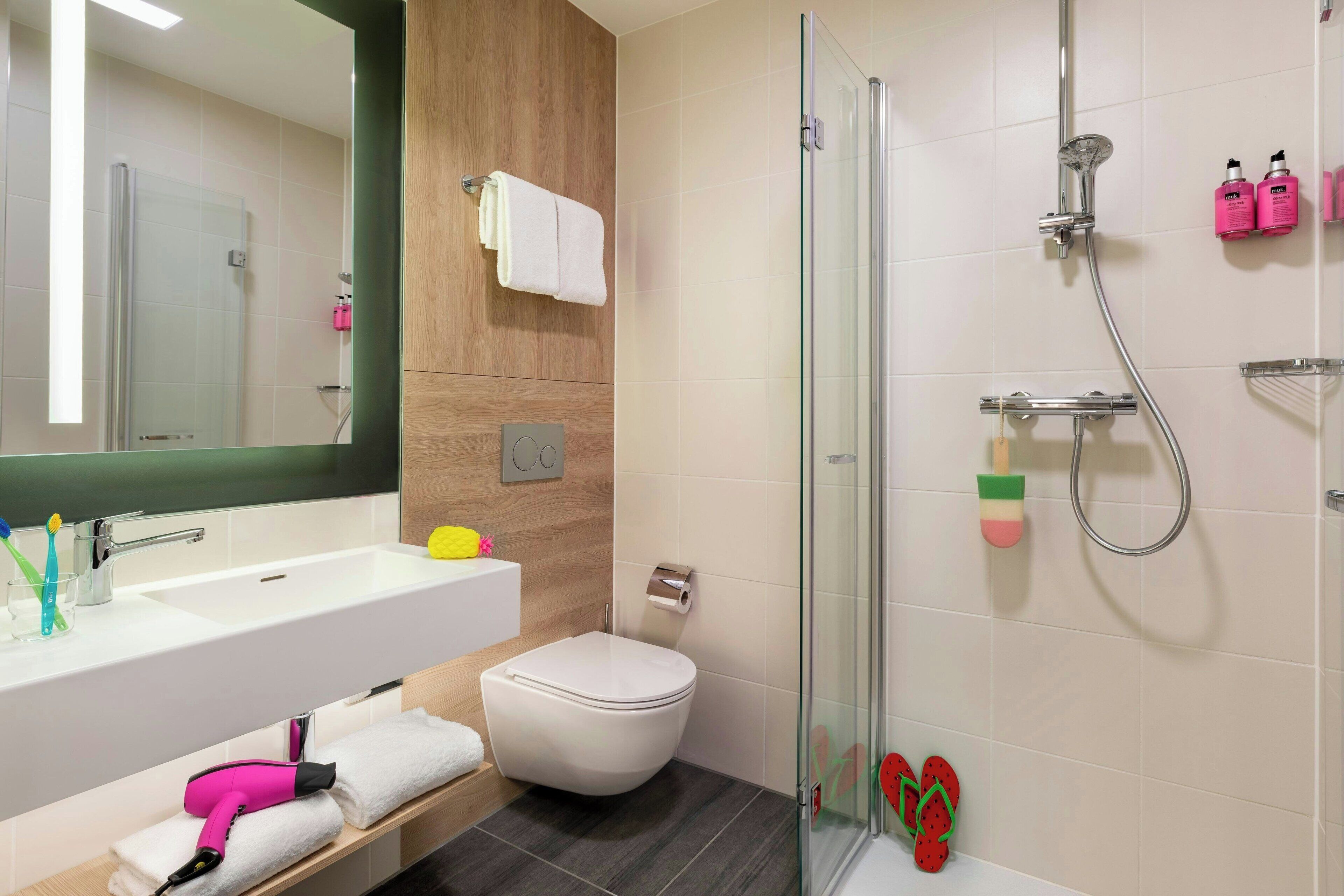 A modern bathroom with a glass-enclosed shower, a white sink, and a toilet.