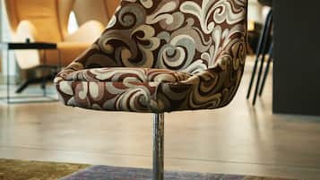A modern chair with a patterned fabric, a metal base, and a colorful rug on the floor.