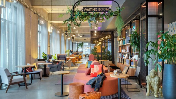 A modern waiting room with comfortable seating, a 'Waiting Room' sign, and a 'All Aboard!' sign. - Moxy Berlin Ostbahnhof (Berlin)