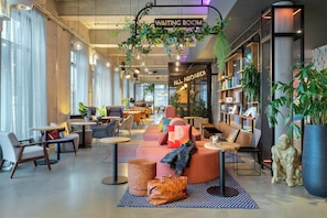 Una sala de espera moderna con asientos cómodos, un cartel que dice 'Waiting Room' y un cartel que dice 'All Aboard!'.