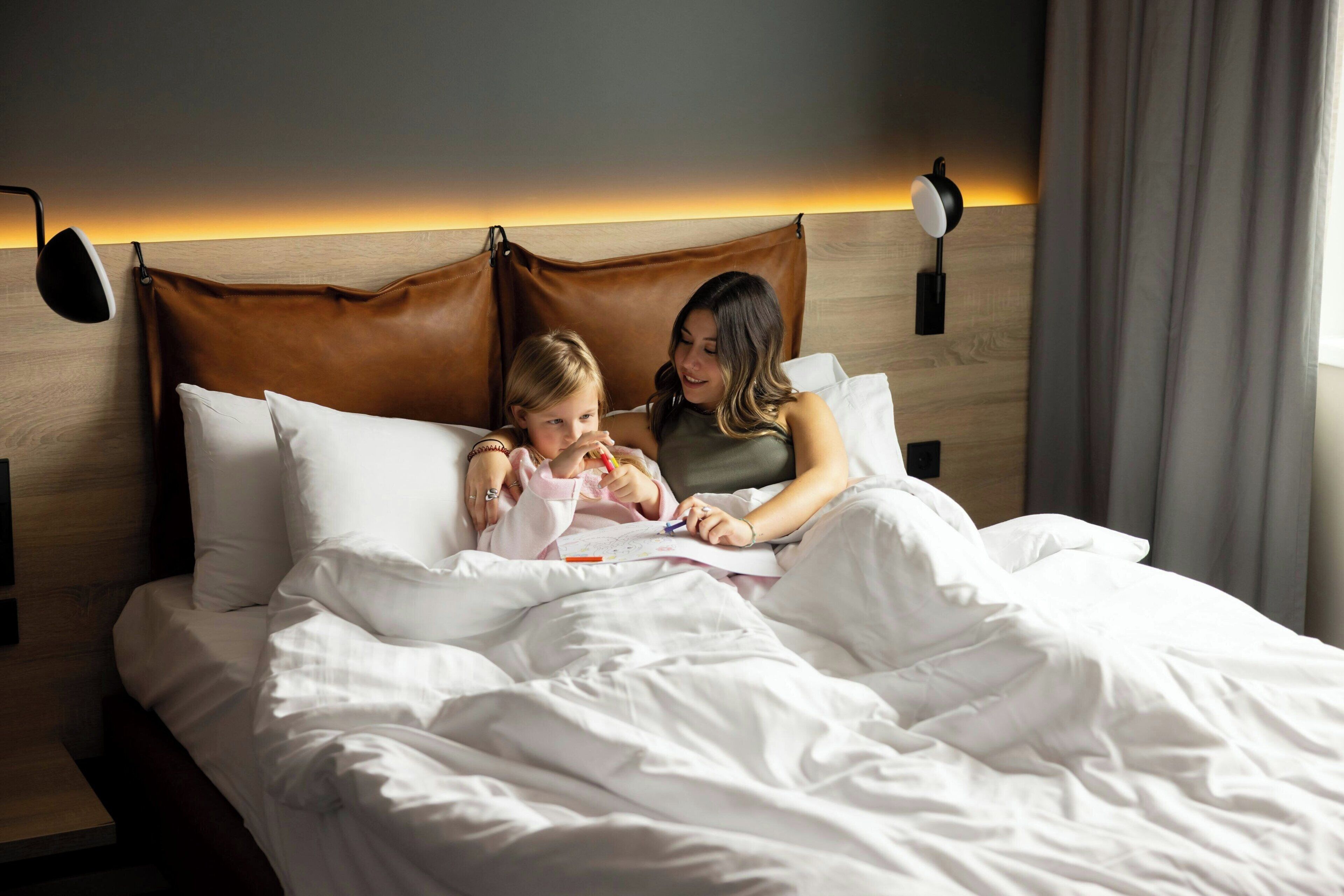 A hotel room with a large bed, a wooden headboard, and two bedside lamps.