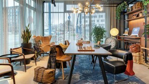 A modern lounge area with a large table, chairs, and a chessboard. - Moxy Berlin Ostbahnhof (Berlin)