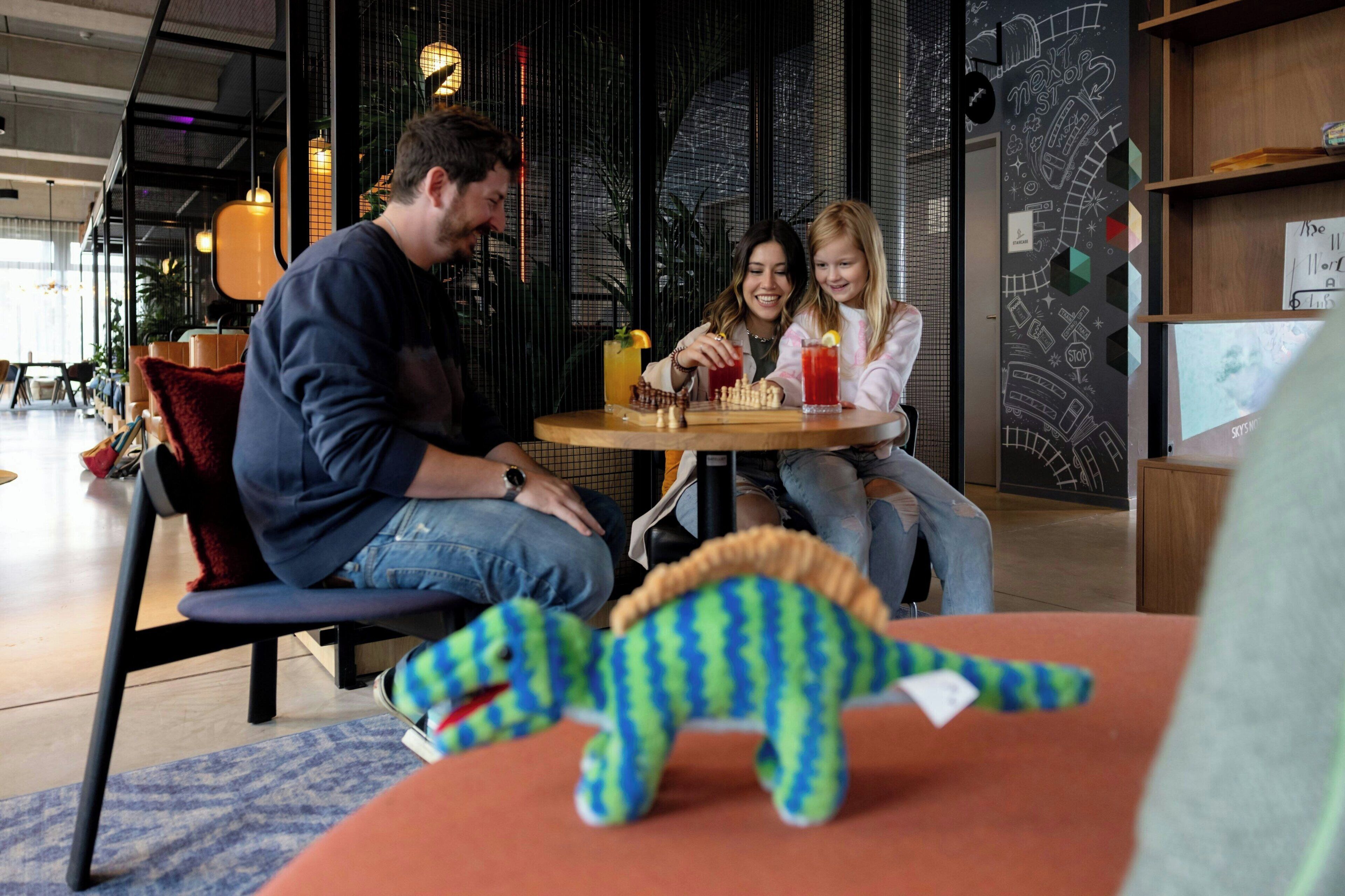 Una familia cenando en una mesa con un juguete de dinosaurio encima.
