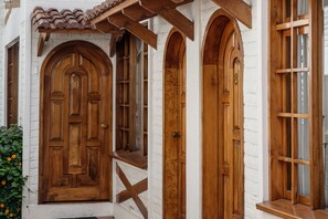 A white building with a wooden door and arched windows. - Apartamentos Los Quipus (Quito)