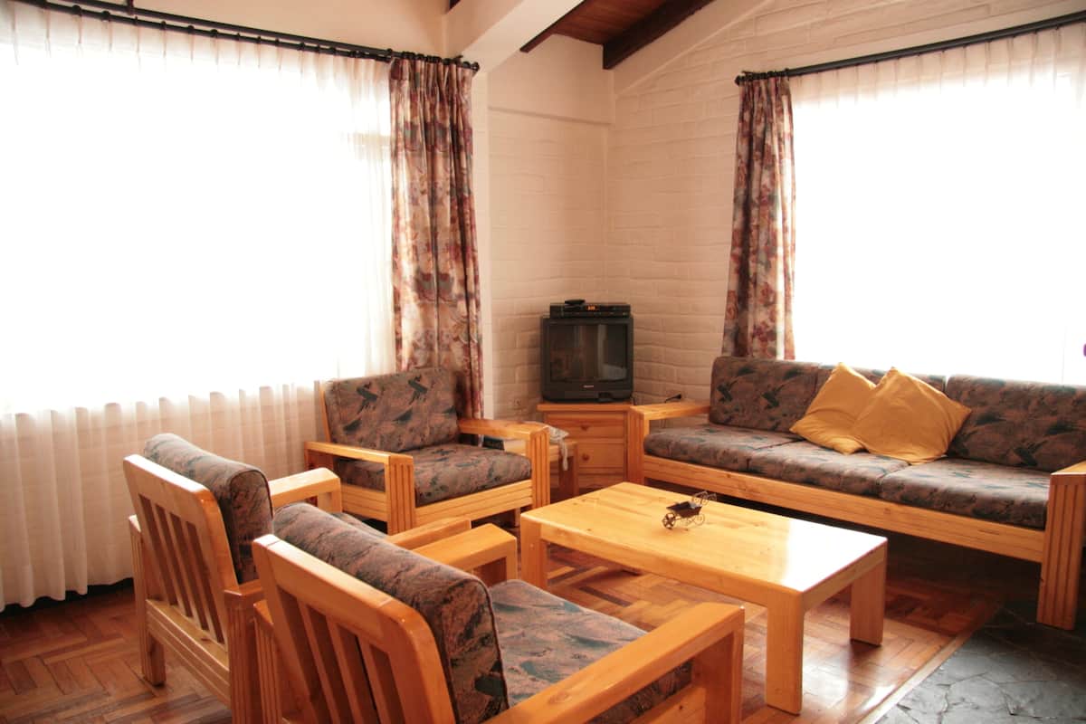A cozy living room with a sofa, two armchairs, a wooden coffee table, and a television.