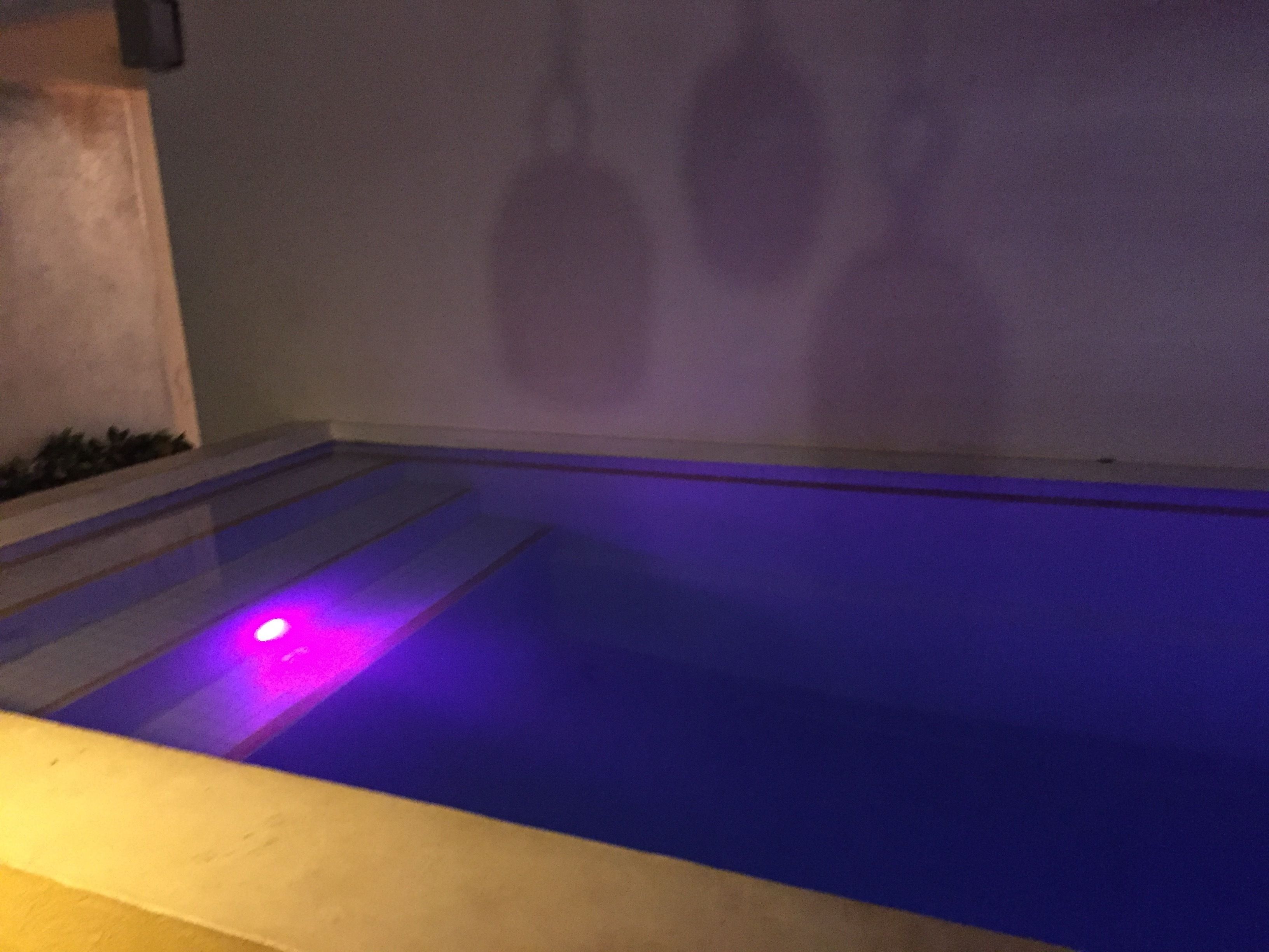 A swimming pool with a purple light on the edge.