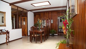 Un coin repas avec des meubles en bois, un grand miroir et des plantes en pot.