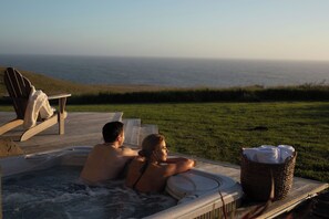 A couple relaxing in a hot tub with a view of the ocean.