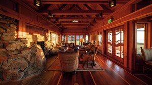 A log cabin interior with stone walls, wooden floors, and large windows. - The Inn at Newport Ranch (Fort Bragg)