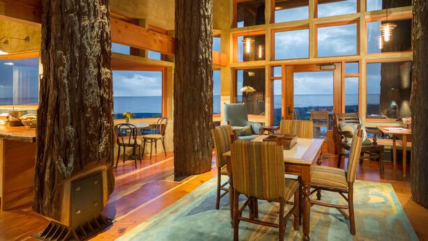 A spacious room with a large wooden table, chairs, and a view of the ocean. - The Inn at Newport Ranch (Fort Bragg)