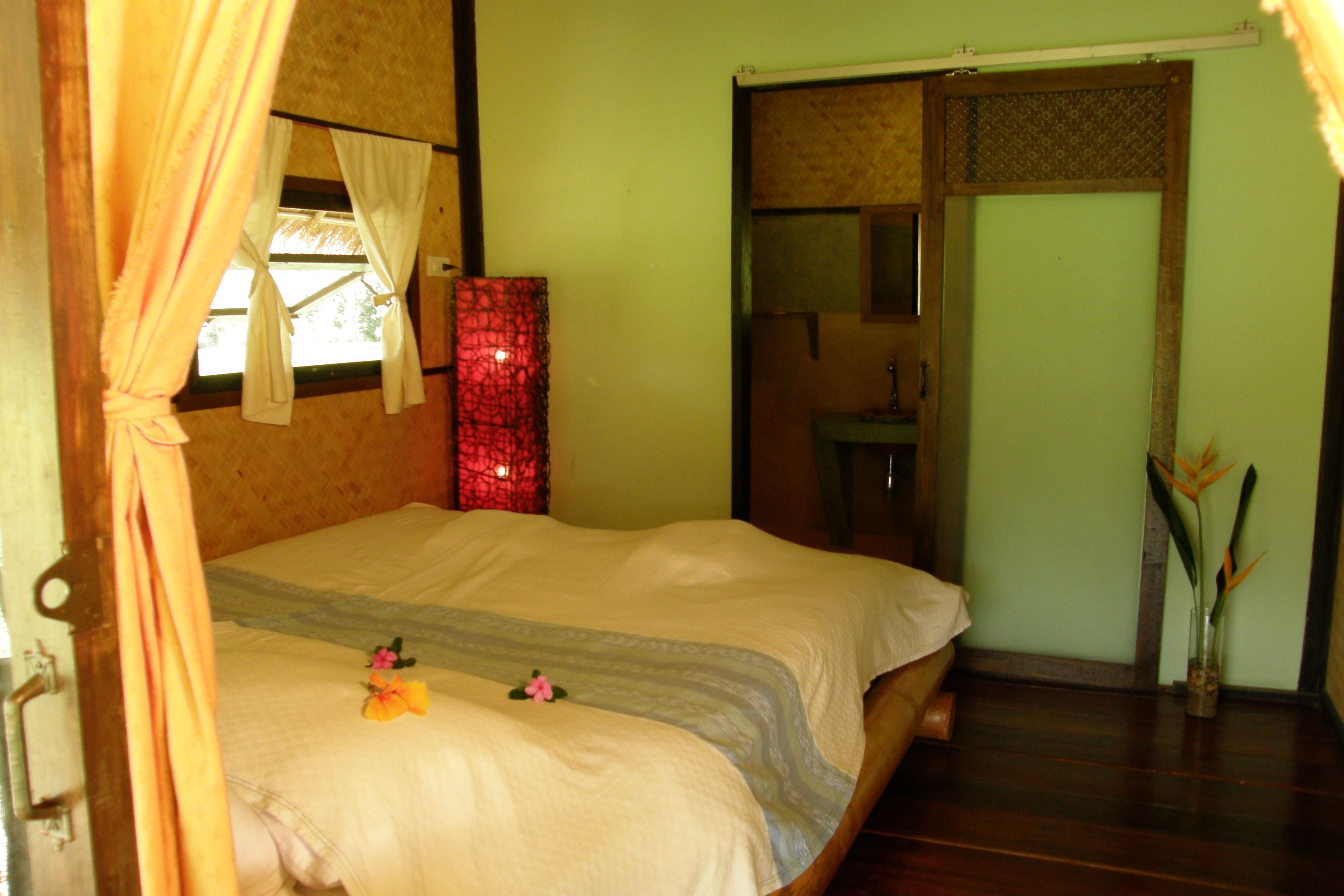 A bedroom with a bed, a nightstand, a mirror, and a door.