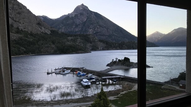 A lake with boats docked at a pier, surrounded by mountains. - Alun Nehuen (San Carlos de Bariloche)