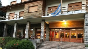 A building with a stone facade, wooden balconies, and a flag. - Alun Nehuen (San Carlos de Bariloche)