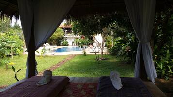 Relax by the serene pool surrounded by lush greenery and a well-maintained lawn.