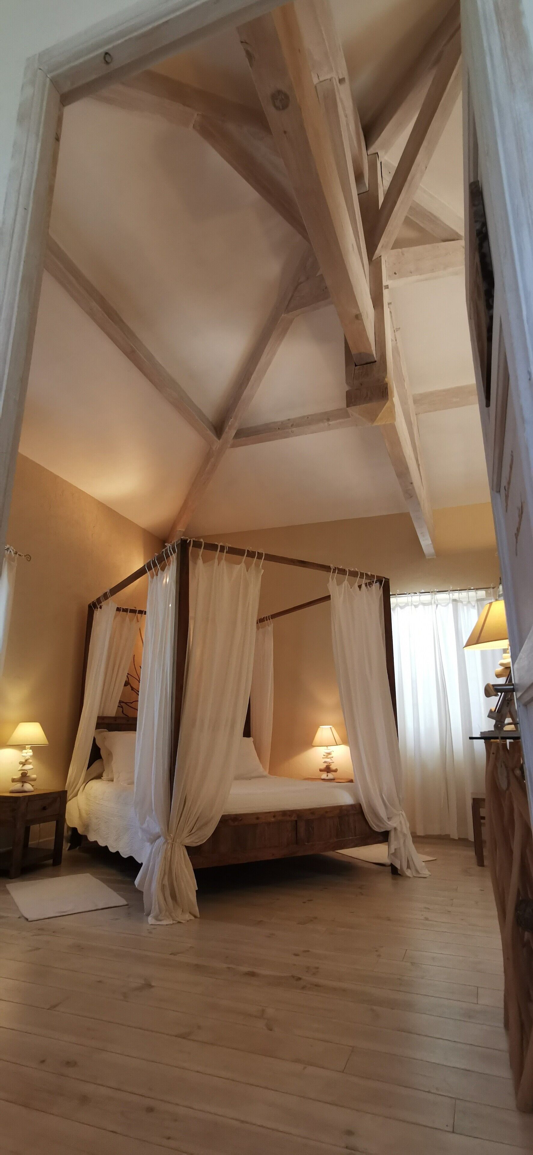 Une chambre à coucher avec un lit à baldaquin, des poutres en bois et un plancher en bois.