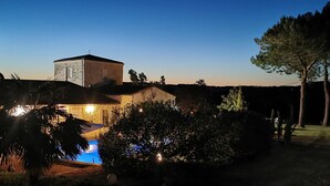 A building with a swimming pool, surrounded by trees and a clear sky.