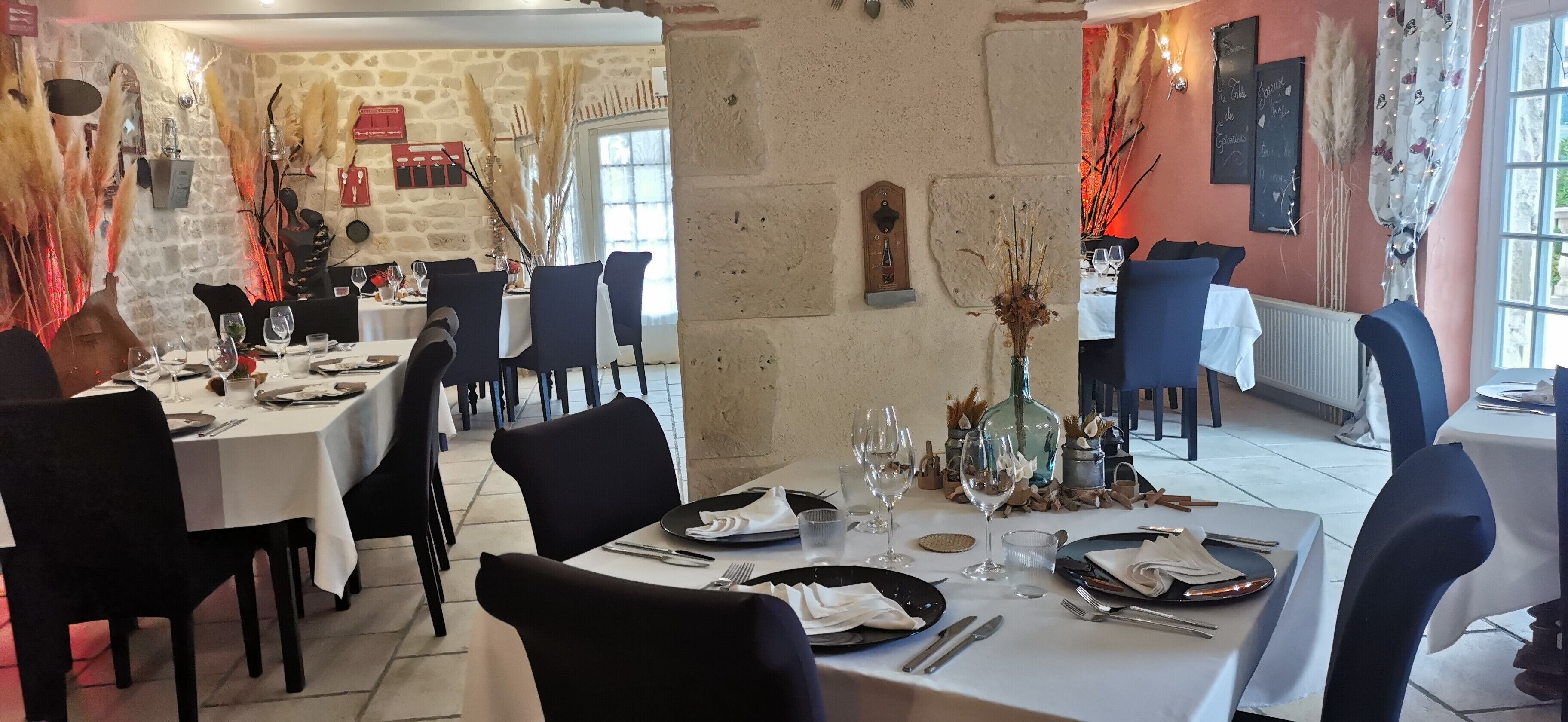 En restaurang med väggar av sten, svarta stolar och vita dukar.