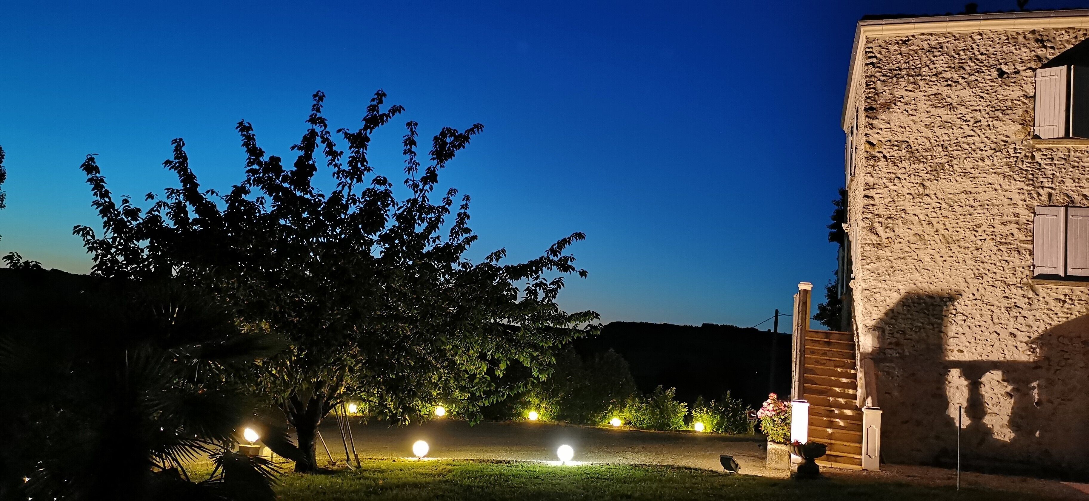 A building with a stone facade, a tree in the foreground, and a well-lit pathway.