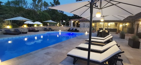Una piscina al aire libre, una piscina climatizada, sombrillas