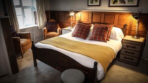 Une chambre confortable avec un lit en bois, deux lampes de chevet, une chaise, une table de chevet et une fenêtre avec des rideaux.