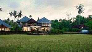 A large, multi-story house with a well-maintained lawn and several palm trees in the background. - Ifiele'ele Plantation (Fasito'o Uta)