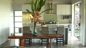 A modern kitchen with white cabinets, a stainless steel range hood, and a microwave. - Ifiele'ele Plantation (Fasito'o Uta)