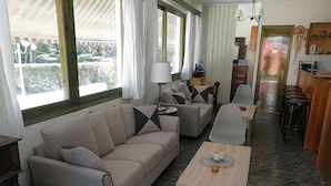En moderne stue med sofa, spisebord og et køkkenområde med barstole.