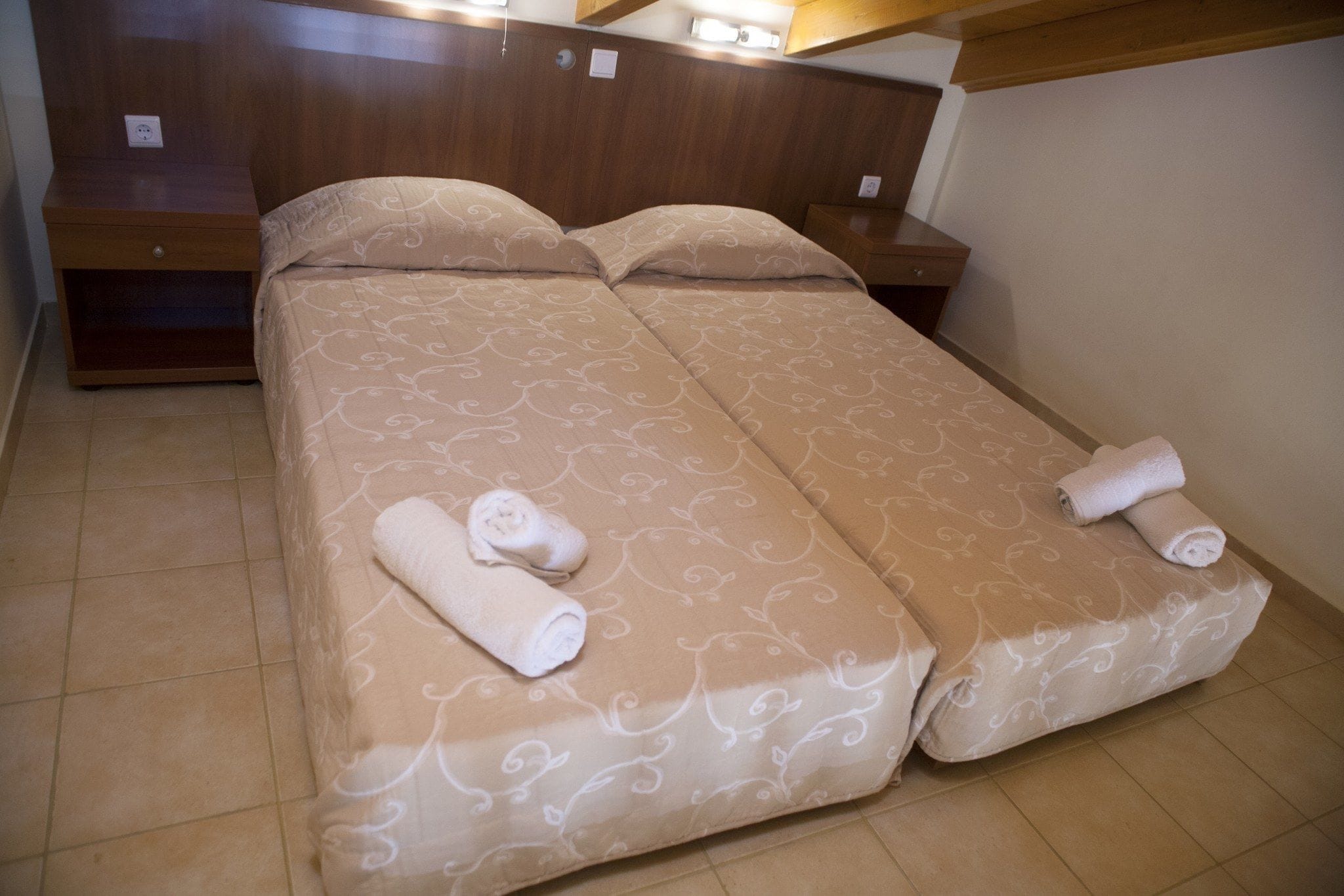 Un lit double avec une couvre-lit à motifs, deux oreillers et deux serviettes enroulées posées sur le lit.