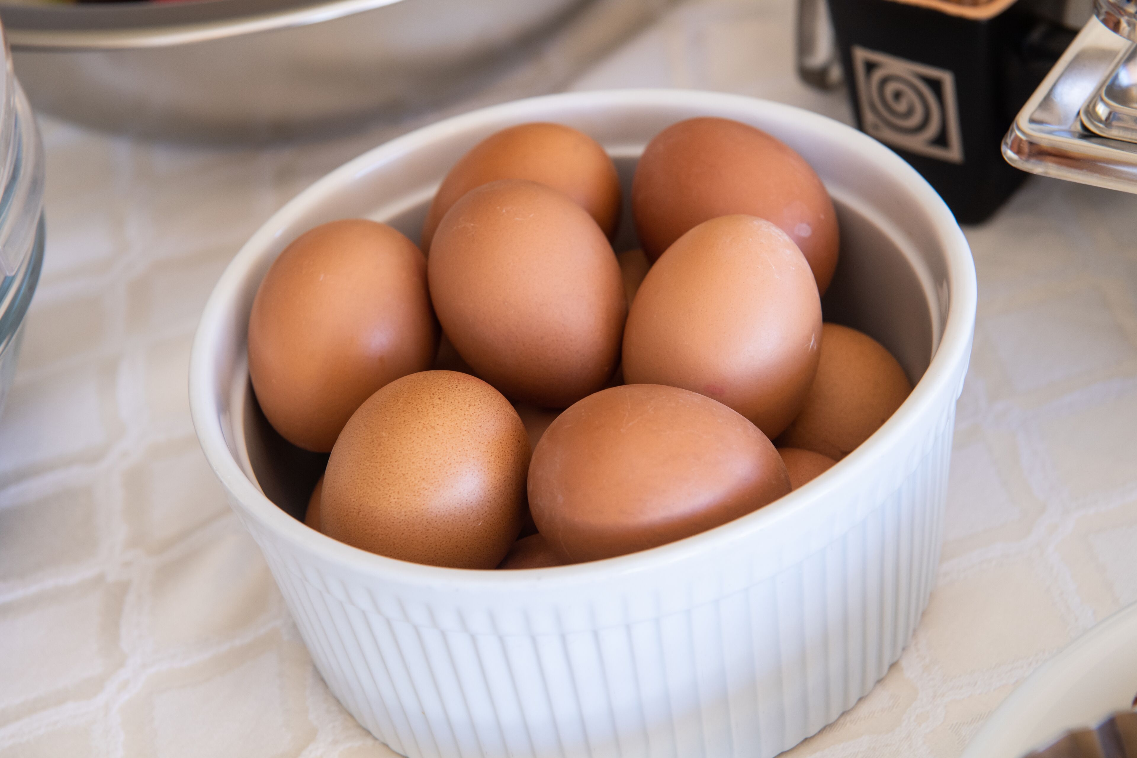 A white ceramic bowl containing several brown eggs.