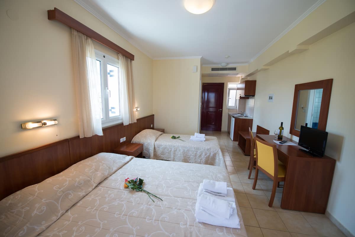 Ein Hotelzimmer mit zwei Betten, einem Schreibtisch mit Fernseher und einer Essecke.