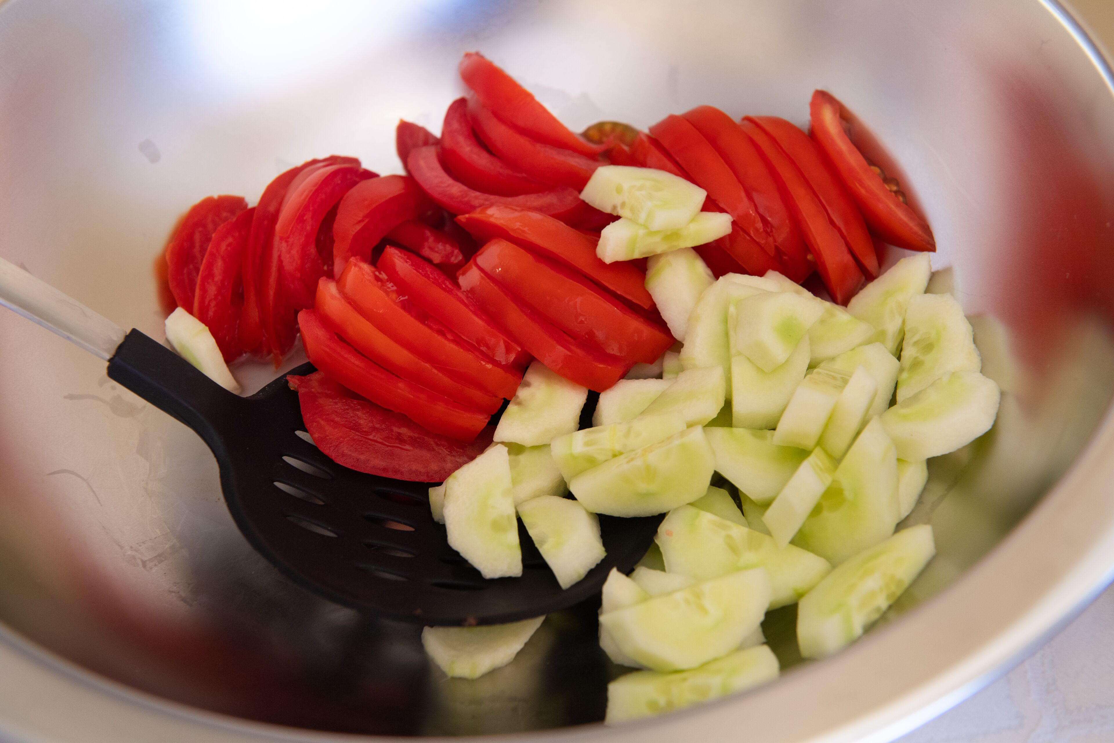 A bowl containing sliced red tomatoes and cucumbers.