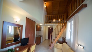 Un amplio espacio habitable con una escalera de madera, una mesa de comedor con sillas, un sofá y una televisión.