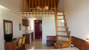 Un dormitorio con una cama grande, un escritorio, una silla, un televisor y una escalera de madera.
