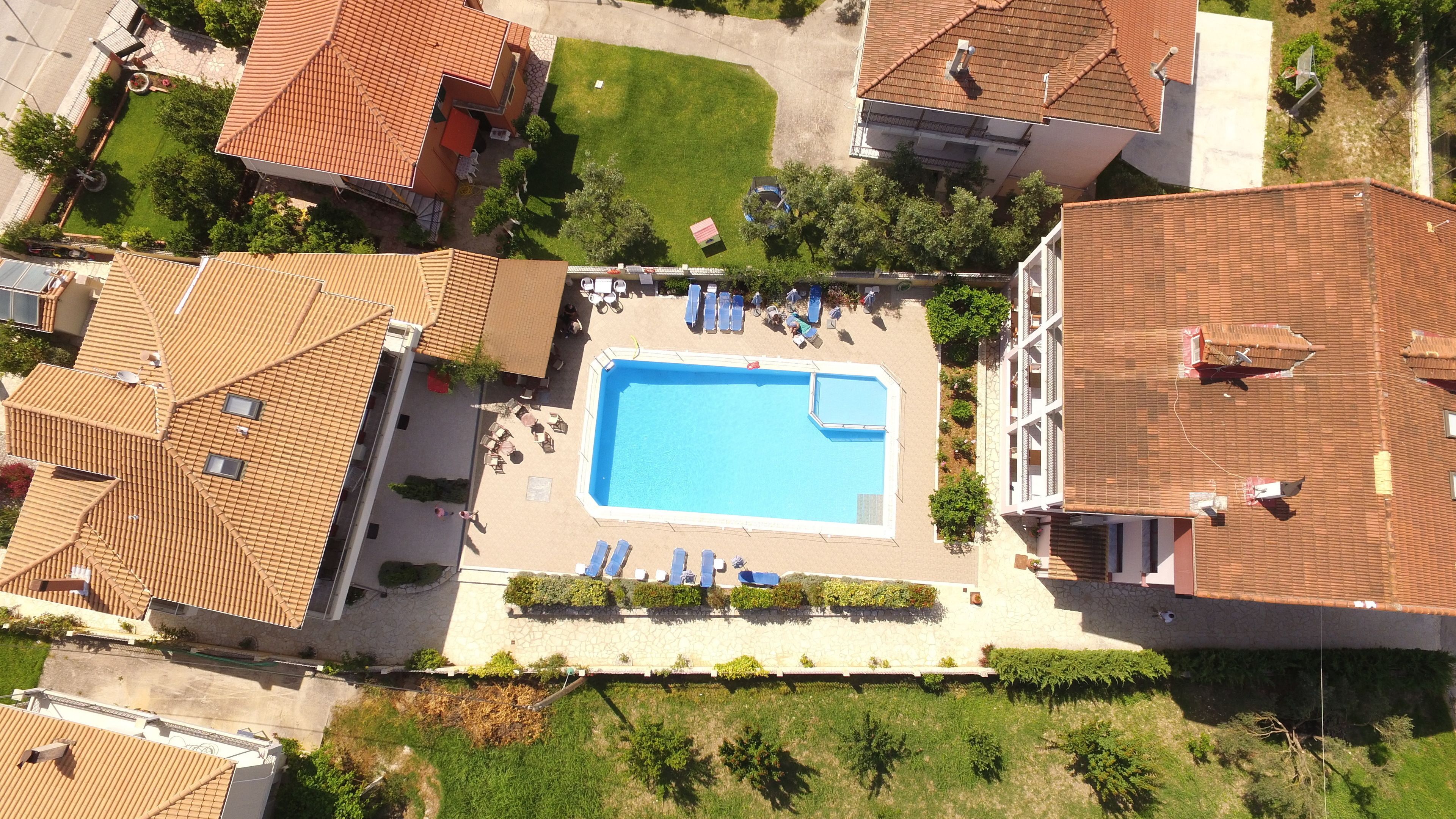 Vista aérea de una zona residencial con piscina rodeada de sillas de descanso y un muro de piedra.