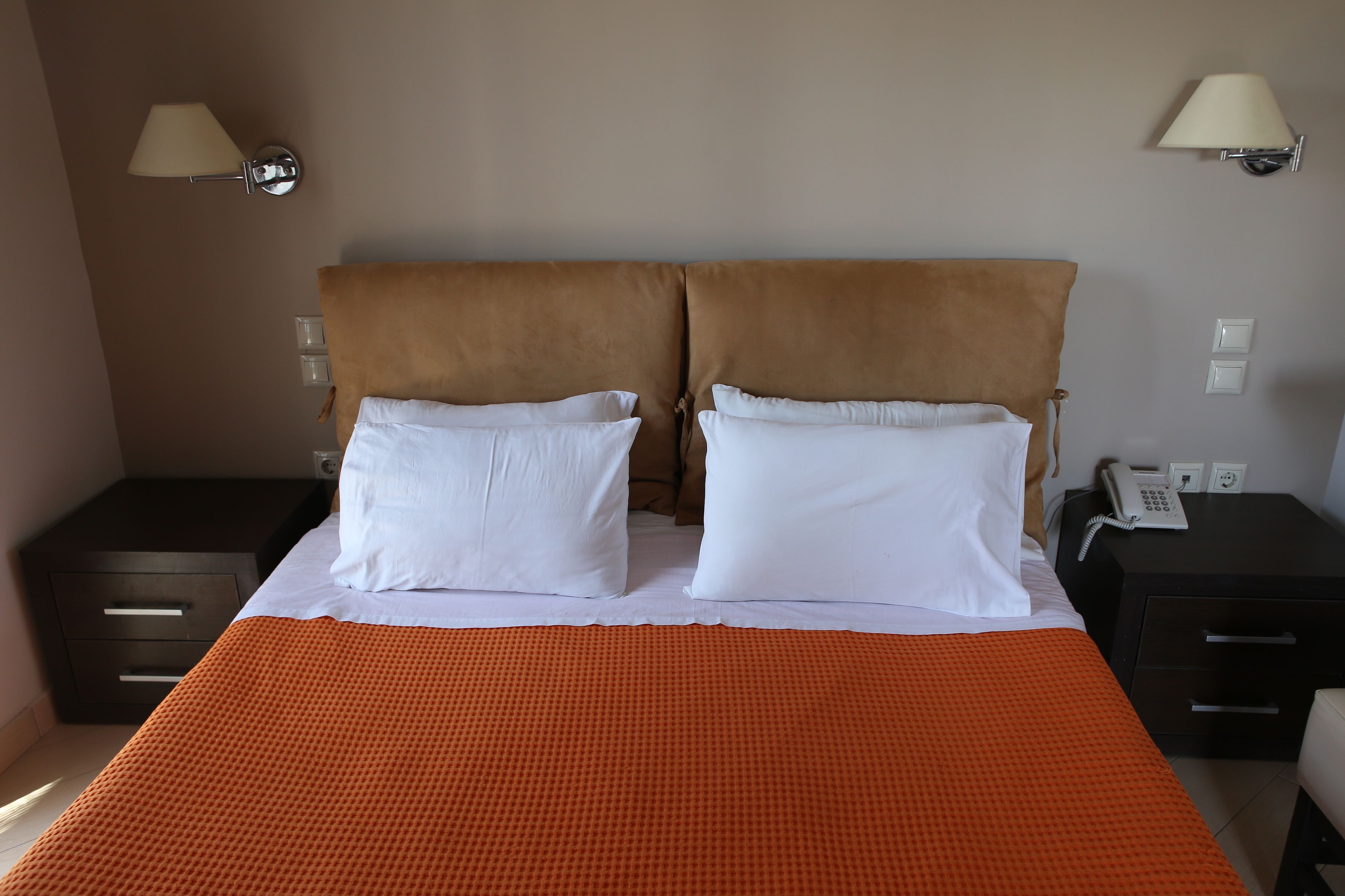 Una habitación de hotel con una cama grande, dos mesitas de noche y dos lámparas de pared.