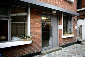 A brick building with a glass door entrance, stone steps, and flower baskets on the windowsills. - Seochon B&B Suran (Seoul)