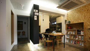 Un área de cocina compacta con una mesa de comedor, sillas y una estantería llena de libros.