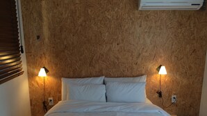 Un dormitorio con cabecera de madera, dos lámparas de noche y una colcha blanca.