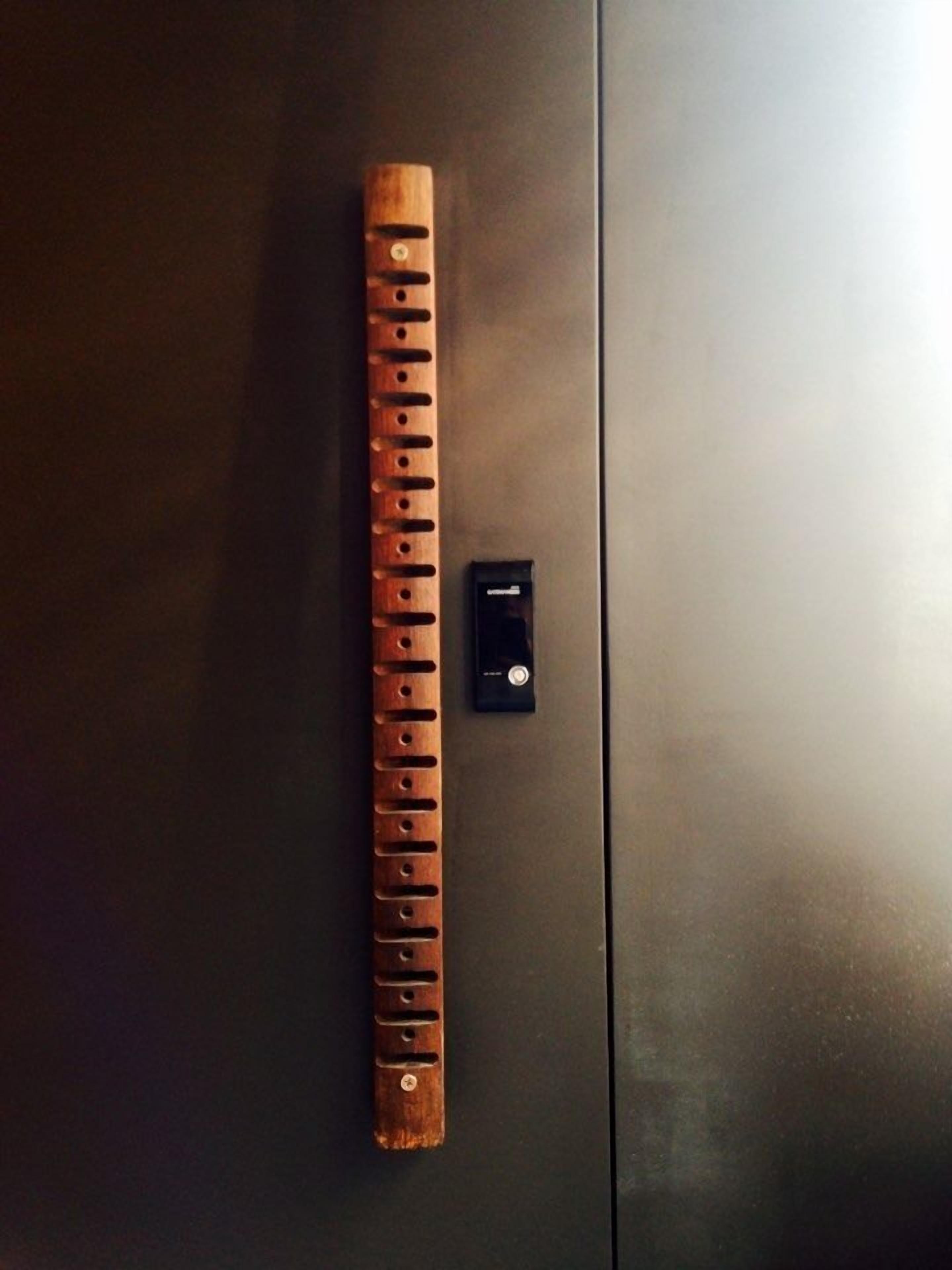 A wooden flute placed on a dark surface next to a black object.