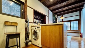 A laundry area with a washing machine, a chair, and a wooden cabinet. - Nook Seoul (Seoul)