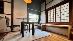 A traditional Japanese-style room with tatami flooring, a low table with chairs, a large shoji screen window, and a hanging light fixture. - Nook Seoul (Seoul)
