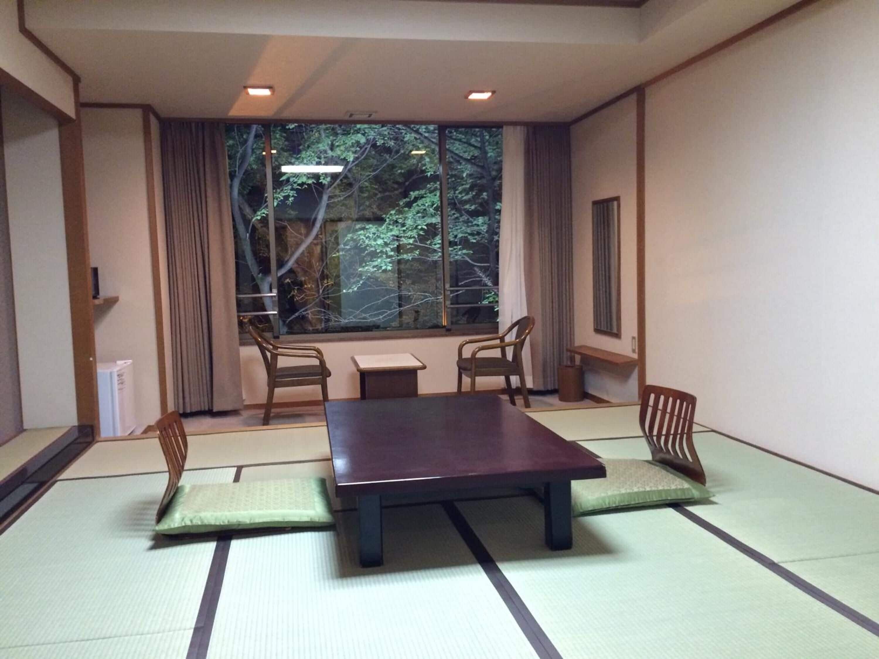 Una habitación japonesa tradicional con suelo de tatami, una mesa baja y cuatro sillas.