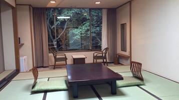 Una habitación japonesa tradicional con suelo de tatami, una mesa baja y cuatro sillas.