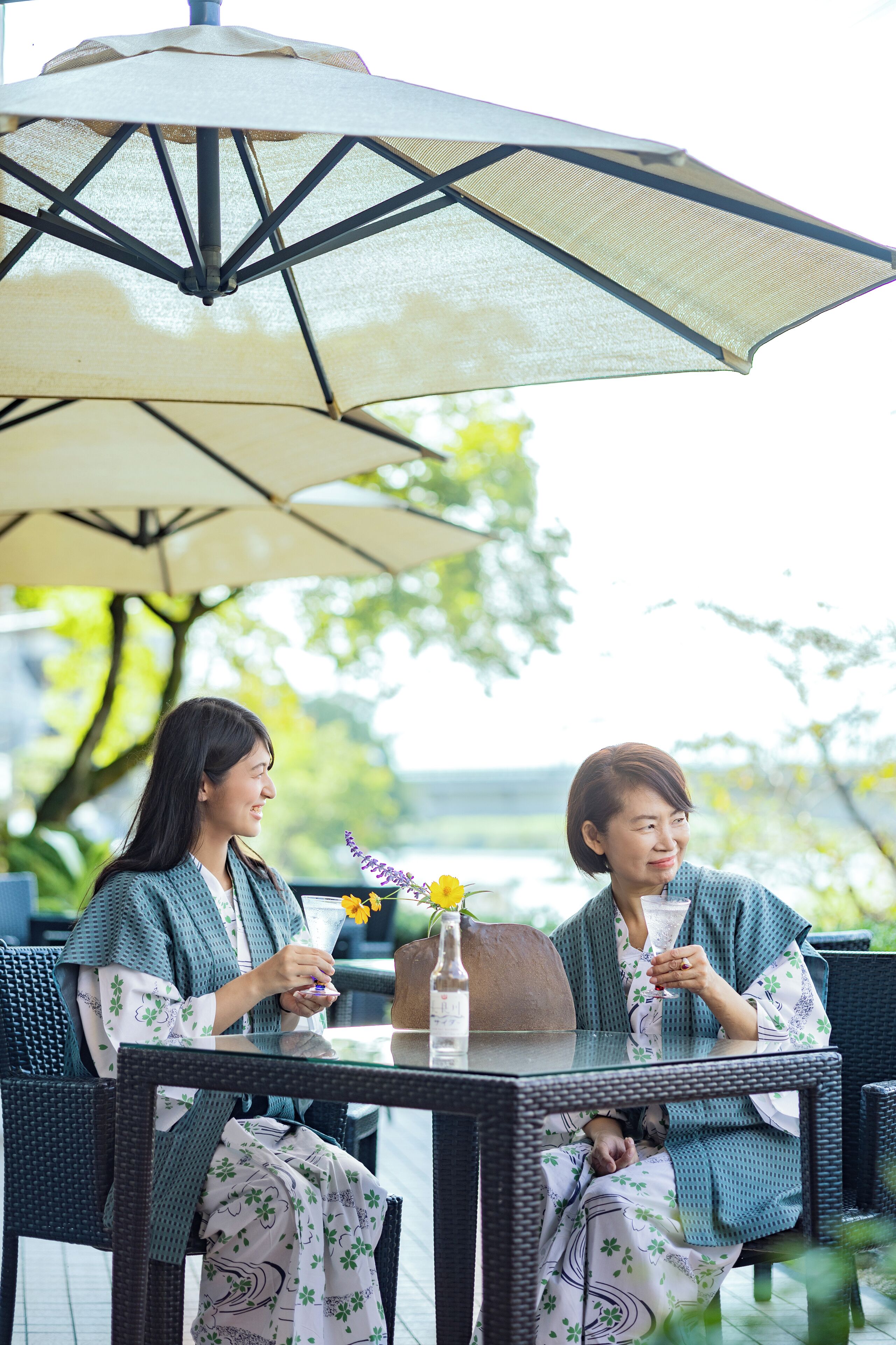 Two people seated at a table with a large umbrella overhead.