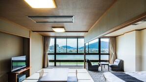 A hotel room with a large window, a bed, a TV, a table, and a chair. - Hotel Park (Gifu)