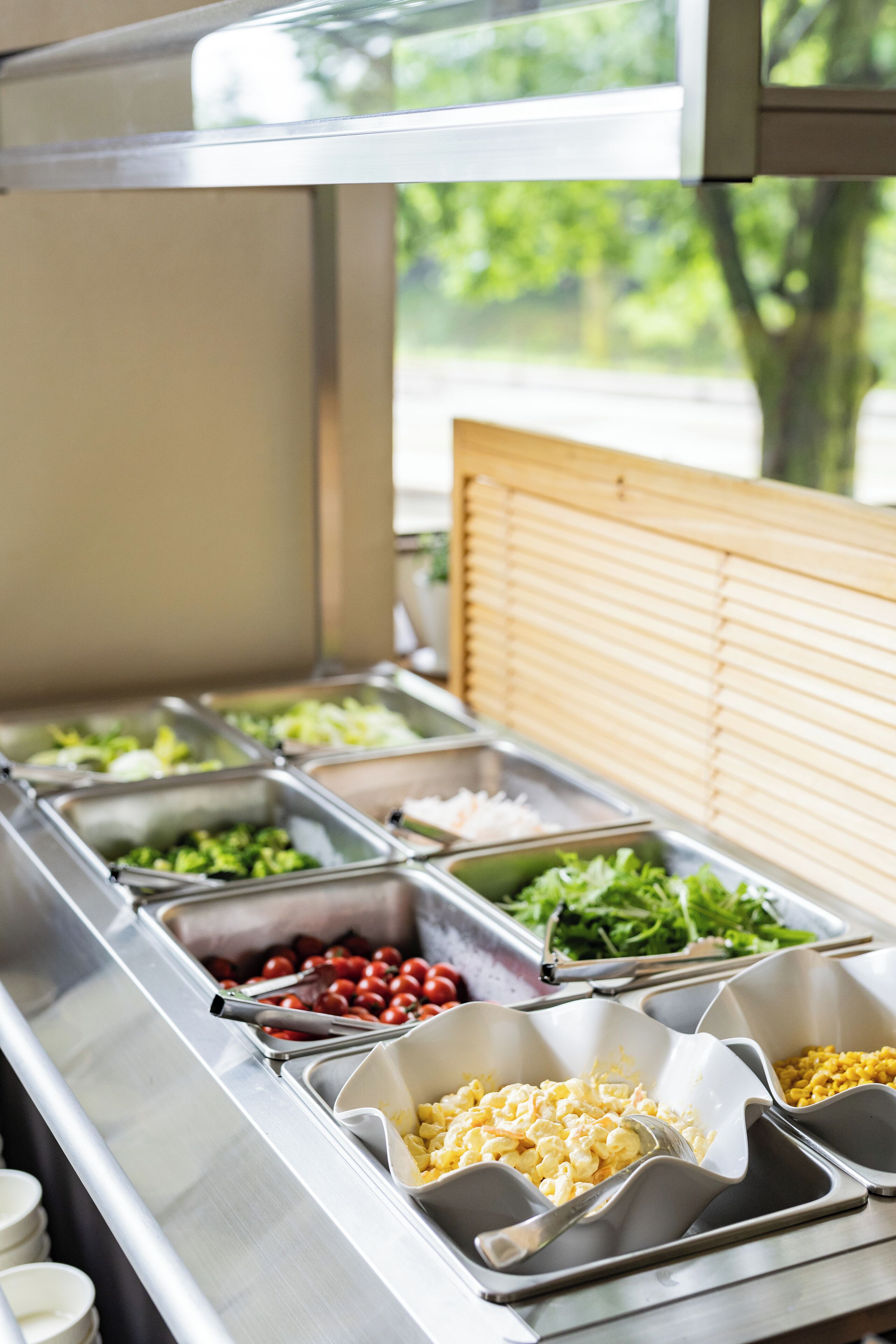 A buffet with various food options including salads, fruits, and pasta.